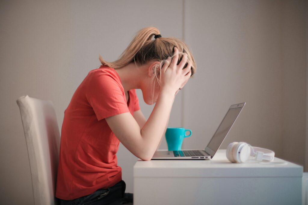 Woman at laptop frustrated by outdated asset management marketing workflows.